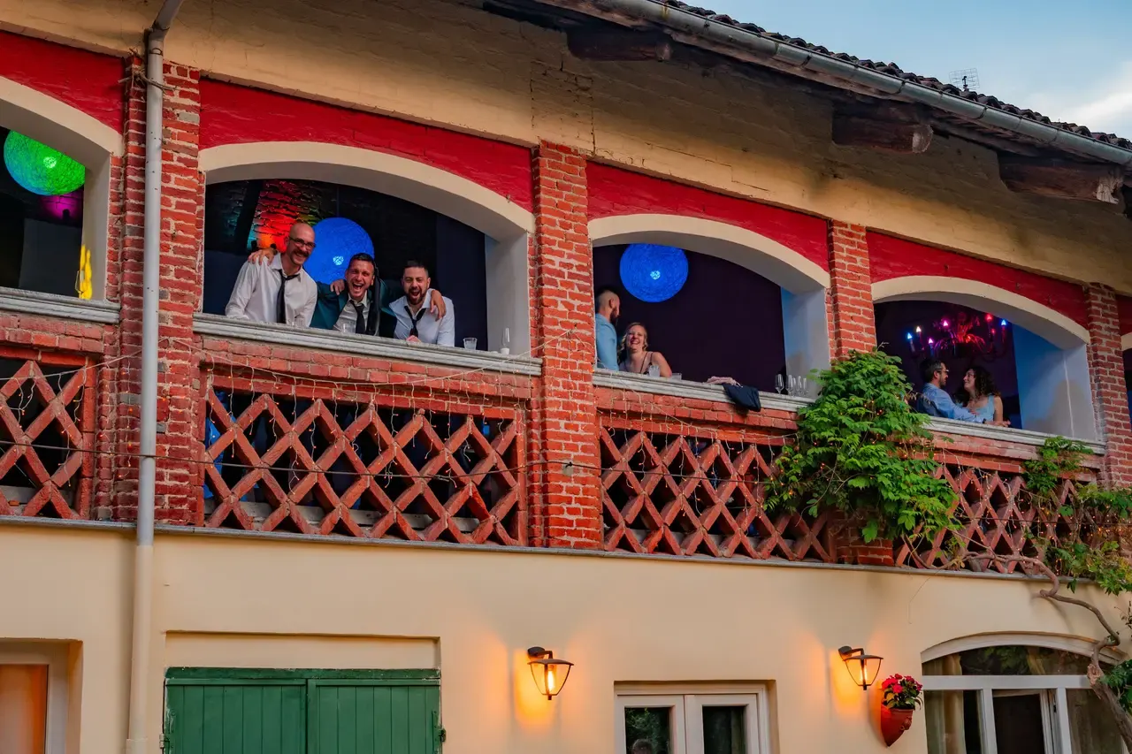 Le arcate della sala superiore di sera, con gli invitati affacciati che ridono e le sfere luminose colorate